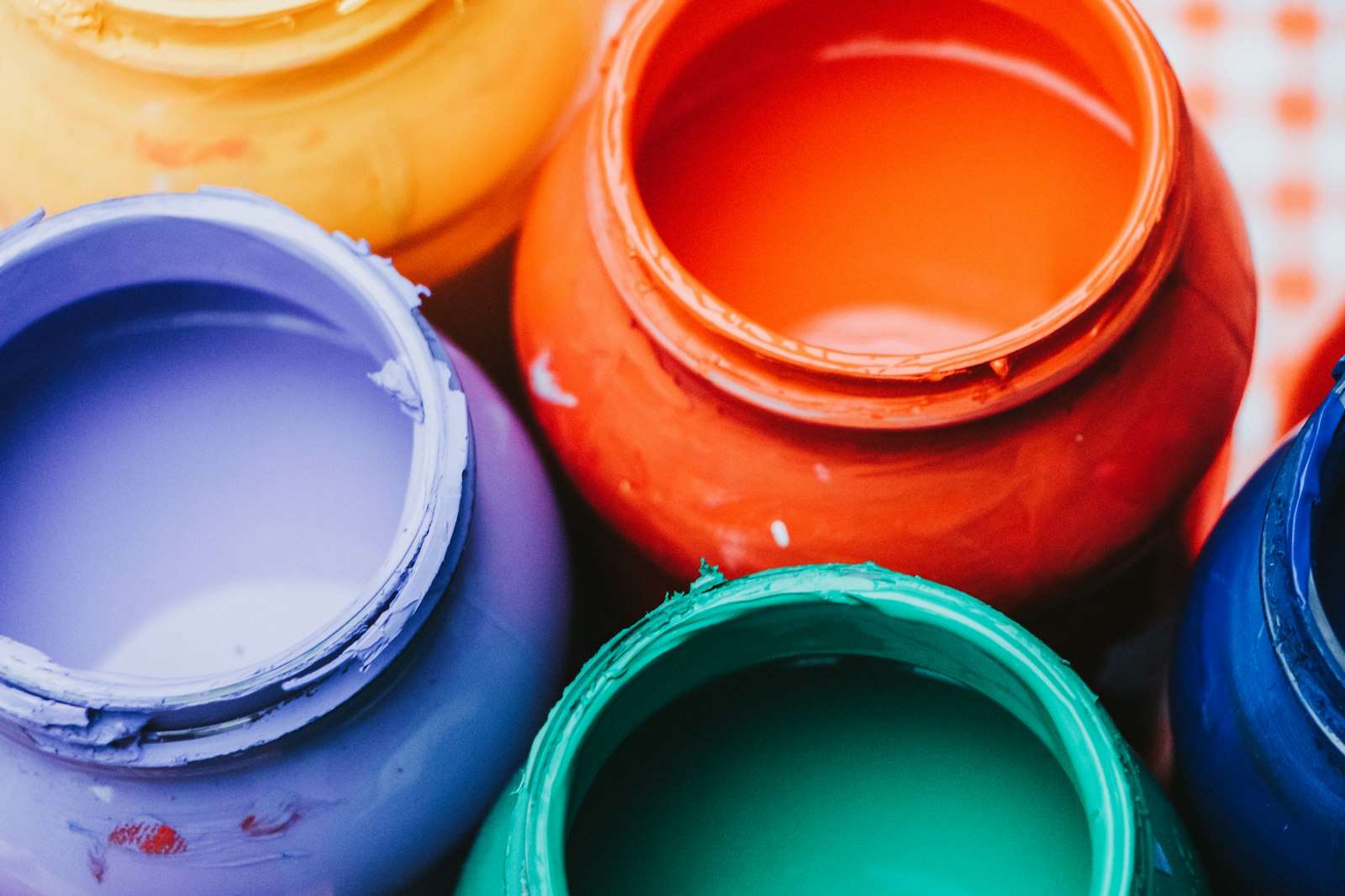 Open tubs of purple, orange, green and blue paint seen from above