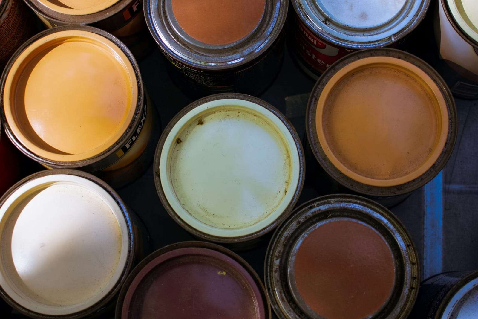 Open tins of paint in warm and blue tones seen from above