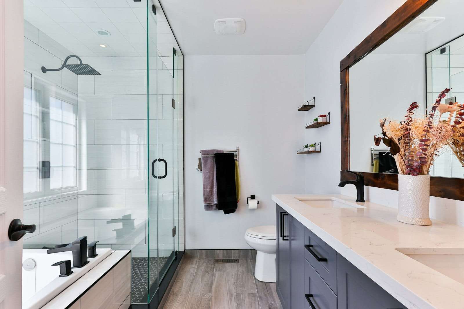 Bright bathroom with a glass shower, white tiles and a vanity
