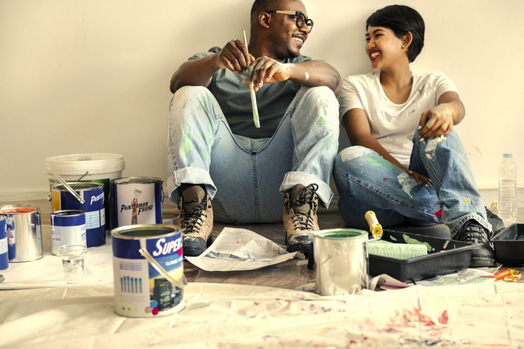 Couple painting house wall